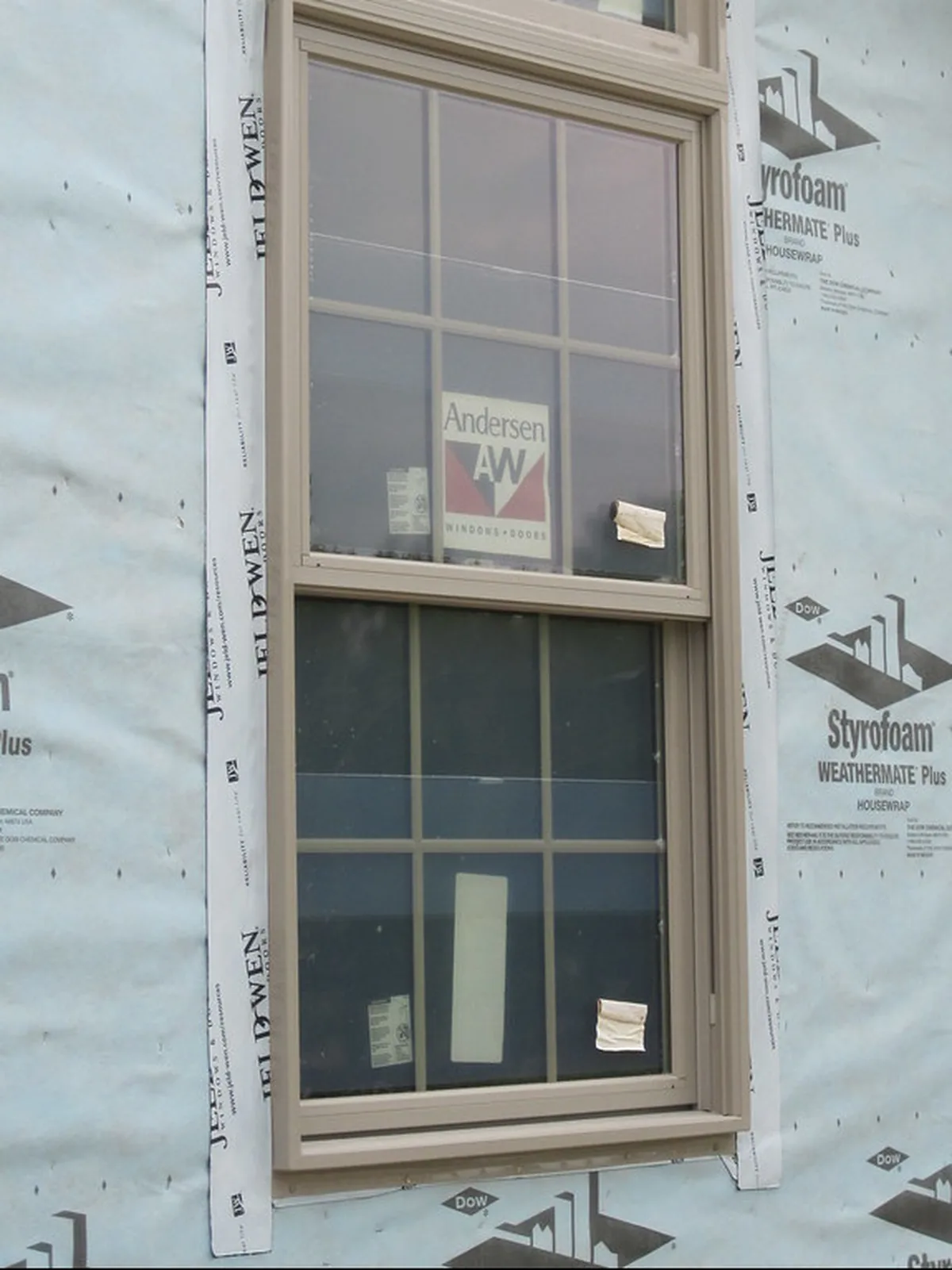 A new energy efficient window for a McDonough GA house set and flashed in the opening, its rating label still on the glass